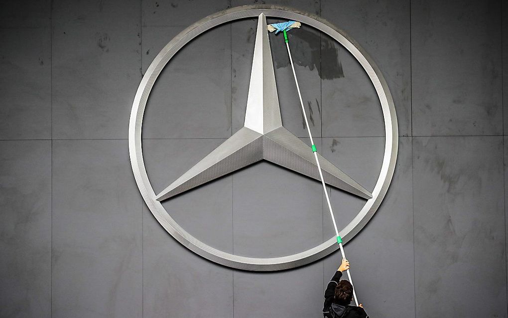 Een schoonmaker maakt het logo van automerk Mercedes schoon aan de vooravond van een internationale autobeurs in Frankfurt am Main, Duitsland. beeld EPA