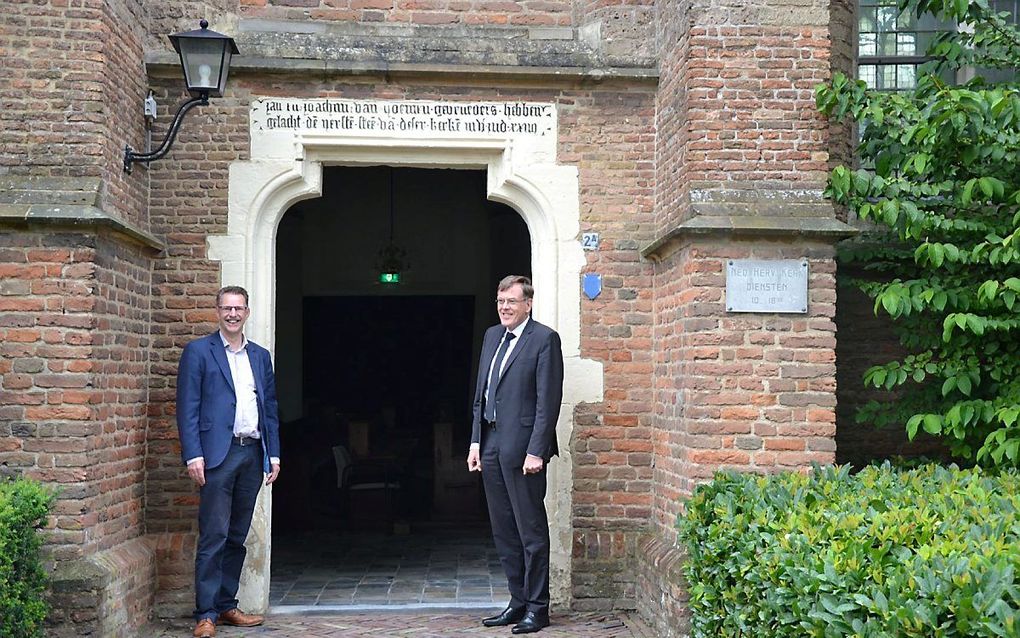 Bart van Kleef en ds. R. van de Kamp (r.) voor de open deuren van de dorpskerk in Opheusden. beeld hhg Opheusden