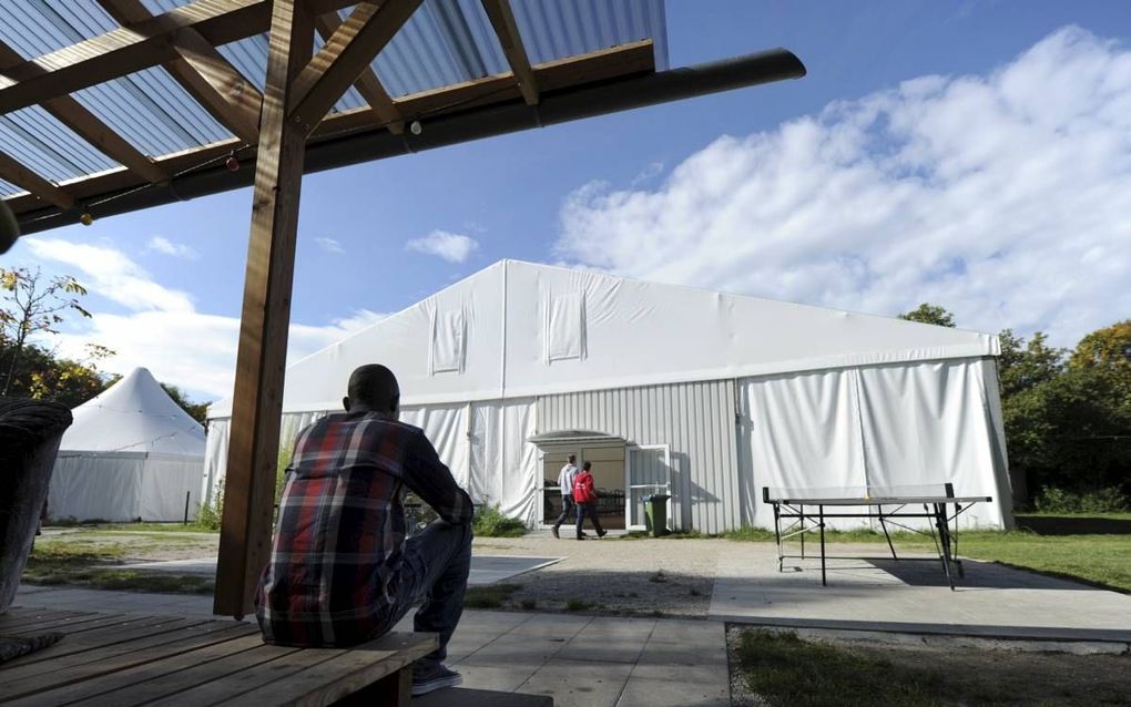 Een vluchteling zit alleen voor een tent in een asielopvang in München. Steeds vaker heeft er geweld plaats tegen christenen in Duitse asielzoekerscentra. beeld EPA