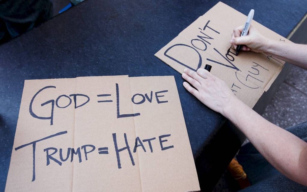 NEW YORK. ”God is liefde, Trump is haat”, schreef een vrouw gisteren op een karton, voordat ze zich voegde bij een groep demonstranten in New York. De gedoodverfde presidentskandidaat Donald Trump ontmoette op dat moment zo’n 500 evangelicale leiders. bee