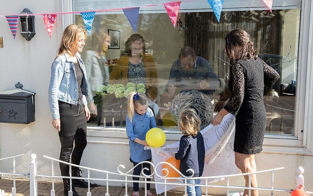 Gerrie Rozendaal uit IJsselmuiden werd donderdag 65 jaar. Zij en haar man Dick kregen feestelijke raamvisite van hun dochters Marianne (l.), Petra (r.) en de kleinkinderen Eva en Lev.  beeld RD, Anton Dommerholt