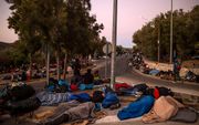 Migranten moeten op de grond slapen nadat vluchtelingenkamp Moria op het Griekse eiland Lesbos grotendeels in vlammen opging. beeld AFP, Angelos Tzortzinis