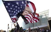 Een aanhanger van Trump zwaait met een enorme campagnevlag in Tulsa, Oklahoma. beeld AFP