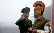 Een Chinese en Indiase grenssoldaat groeten elkaar. beeld Diptendu DUTTA / AFP