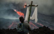 Een persoon met een kruis kijkt naar de lava die langs de Pacaya-vulkaan stroomt, in San Vicente Pacaya, Guatemala. Katholieke inwoners van het dorp El Patrocinio hebben de afgelopen zeven weken elke woensdag een pelgrimstocht gemaakt om te bidden dat de lava de nabijgelegen steden niet zou bereiken. beeld EPA, Esteban Biba