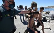 Spaanse soldaten en politieagenten helpen een paar jonge migranten die net op het strand van Ceuta zijn aangekomen. beeld AFP, Antonio Sempere