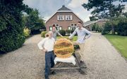 Vader Dick van Woudenbergh (54) en zijn zoons  Gerrit (16) en Tim (23) met een boerenkaas van 150 kilo, speciaal gemaakt voor de Woerdense graskaasdag in juni.  beeld Sjaak Verboom