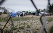 Vlak voor de doorgang door het grenshek tussen Hongarije en Servië ligt een kamp waar vluchtelingen wachten om doorgelaten te worden. beeld RD, Evert van Vlastuin