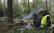 Een vader en een zoon koken een potje in het bos in de Belgische Ardennen tijdens een vader-zoonsurvival van de Jeugdbond Gereformeerde Gemeenten. beeld JBGG, Sjaak Jacobse