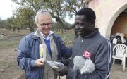 Evangelist Van den Boogaart (l.) overhandigt Abraham uit Ghana een Engelse versie van ”De Christenreis” van Bunyan. beeld RD