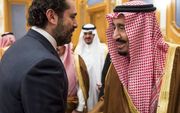 De Saudische koning Salman bin Abdulaziz al-Saud (r.) schudt in het koninklijk paleis in Riyad de hand van de onlangs afgetreden Libanese premier Saad Hariri (l.), zaterdag. beeld AFP, Bandar al-Jaloud