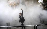 Een Iraanse vrouw trotseert bij de universiteit van Teheran het traangas tijdens een van de demonstraties in het land. beeld AFP