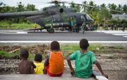 Drie Papoea-jongens kijken toe hoe een Indonesische legerhelikopter landt in Asmat. Daar brak eind vorige maand een dodelijke mazelen-epidemie uit.  beeld AFP,  Bay Ismoyo