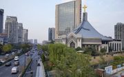 Een groot, geel kruis siert nog altijd het dak van de Chong-Yi-kerk in de Chinese stad Hangzhou. Het valt op tussen de vele grijze gebouwen. Andere kerken moesten hun kruizen wél verwijderen of verplaatsen naar een onopvallender plek. beeld Jaco Klamer