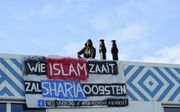 Activisten van Identitair Verzet hangen een spandoek aan de gevel van een nieuwe middelbare islamitische school in Amsterdam. beeld ANP, GinoPress