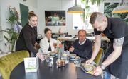 Fleur Visch (l.) serveert met een collega een lunch in maatschappelijk restaurant Het Melkmeisje in Kruiningen. Tweede van rechts is Jan van Blarikom. beeld Dirk Jan Gjeltema