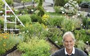 Tuinliefhebber John Bontje (67)  bij zijn unieke bloemenklok in Boskoop. beeld Theo Haerkens