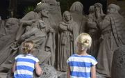 Kinderen bekijken een zandsculptuur waar de wegvoering van Jozef naar Egypte wordt uitgebeeld. beeld RD