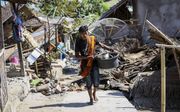 Een bewoner van Lombok probeert wat huisraad in veiligheid te brengen nadat zijn huis zondag na een tweetal aardbevingen instortte. beeld EPA
