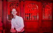 Herman Mussche op zijn nieuwe werkplek, de Oude Kerk in Amsterdam. De kerk kleurt hier nog rood. Op 23 september is de tentoonstelling ”ANASTASIS” (wederopstanding) van kunstenaar Giorgio Andreotta Calò afgesloten, waarna de rode ramen weer worden verwijd