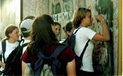Scholieren schrijven op de plek van de moord op Rabin iets op een muur.  beeld Alfred Muller