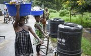 Moeders en kinderen tappen water om zich te wassen en zo besmetting te voorkomen. beeld AFP, Isaac Kasamani.