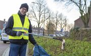Peter van der Spoel haalt een plastic zak uit de struiken. Hij voert actie om zwerfafval in Alblasserdam op te ruimen. beeld Peter Stam