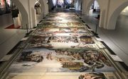 De uitvergrote foto’s van de fresco’s liggen in het midden van de zaal op de grond en kunnen gemakkelijk, in alle rust en ruimte, worden bekeken. beeld RD