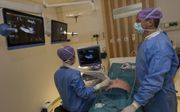 Dick Oepkes (r.) behandelt in het LUMC samen met een echoscopiste een foetus in de baarmoeder.  beeld RD, Anton Dommerholt
