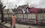 Een vrouw met haar kind staat bij beschadigde gebouwen in Beira, Mozambique, afgelopen zondag. Het grootste deel van Beira ligt in puin, nadat een verwoestende orkaan door de stad raasde. beeld Internation Federation of Red Cross and Red Crescent Societie