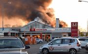 In een autobedrijf in Hulst (Zeeland) woedt een grote uitslaande brand. Daarbij zijn explosies te horen, veroorzaakt door ontploffende gasflessen in de garage. beeld ANP