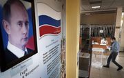 Onder toeziend oog van staatshoofd Poetin brengt een man zijn stem uit voor de wijziging van de grondwet. beeld EPA, Maxim Shipenkov