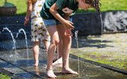 Kinderen zoeken in Nijmegen verkoeling bij een fontein. beeld ANP
