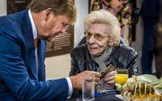 Koning Willem-Alexander in gesprek met een hoogbejaarde vrouw. beeld ANP
