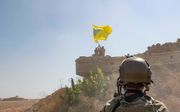 Een Amerikaanse militair kijkt in Noord-Syrië naar strijders van de Syrische Democratische Strijdkrachten. beeld EPA