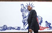 Een Iraniër loopt langs een schildering op een muur van de voormalige Amerikaanse ambassade in Teheran. beeld AFP
