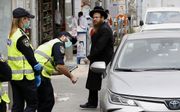 Israëlische politieagenten spreken een automobilist aan bij een checkpoint in Bnei Brak, a stad met een grote ultraorthodox-Joodse populatie bij Tel Aviv. beeld AFP, Jack Guez