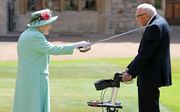 De Britse koningin Elizabeth slaat Tom Moore tot ridder. beeld AFP