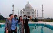 Toeristen nemen een selfie voor het Taj Mahal in India. Nadat de deuren van het mausoleum sinds maart gesloten waren, heropende ze maandag haar deuren. beeld EPA