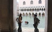 Twee vrouwen bij het overstroomde San Marcoplein in Venetië. beeld EPA