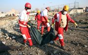 Hulpverleners van het Rode Kruis verzamelen lichamen na de crash bij Teheran. beeld EPA