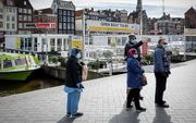 In een uitgestorven Amsterdam lopen toeristen met mondkapjes. beeld ANP, Robin van Lonkhuijsen