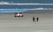 Een politieauto op een bijna leeg strand op Ameland. beeld ANP