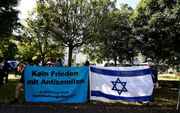 Duitse kerken ondernemen gezamenlijk actie tegen antisemitisme in een postercampagne. Archiefbeeld: Demonstranten tonen vlaggen tegen Jodenhaat bij de start van het proces tegen de man die een aanslag pleegde op een synagoge in het Duitse Halle. beeld AFP