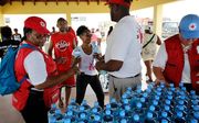 Medewerkers van het Rode Kruis delen water uit aan bewoners in Cay Bay op Sint Maarten. De bewoners van de wijk, die zwaar getroffen is door orkaan Irma, hebben geen beschikking over schoon drinkwater. beeld ANP