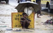 Een jonge Rohngyavluchteling schuilt onder een paraplu in een vluchtelingenkamp in Bangladesh. beeld AFP