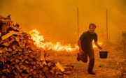 Alex Schenk (15) uit Clearlake Oaks, Californië, probeert zijn huis te redden van de vlammen. beeld AFP