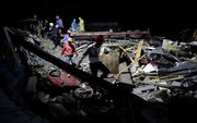 Reddingwerkers zoeken naar vermiste arbeiders in de puinhopen van een ingestort gebouw in Cambodja. beeld EPA