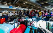 Stapels met tassen en koffers op Eindhoven Airport. Door een storing in het bagagesysteem moeten medewerkers handmatig bagage inchecken. beeld ANP