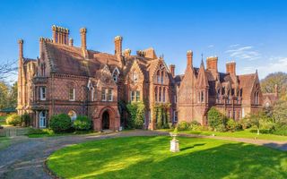 Het gotische gebouw van de All Nations Christian College, met een strakblauw lucht en felgroen gras omheind.